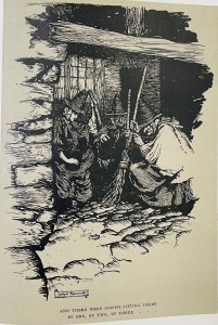 Black and white illustration of three witches huddled in an old shack