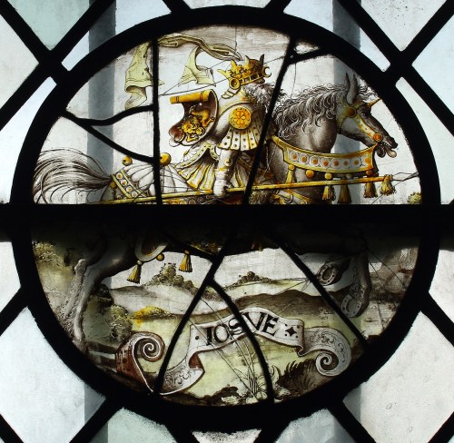 Round panel of stained glass showing Joshua in golden armour mounted on a white horse
